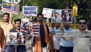 Protest Against Dr. Zakir Naik: Voices for Boycott Rise Amid Controversy Protesters holding Dr. Zakir Naik's picture with a 'Boycott' sign in the background."