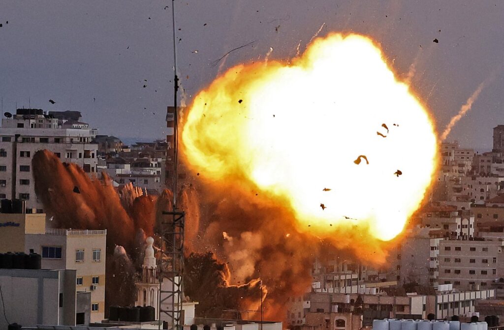 A devastating airstrike in Gaza shows buildings in flames, capturing the human cost of war and ongoing destruction in the region.